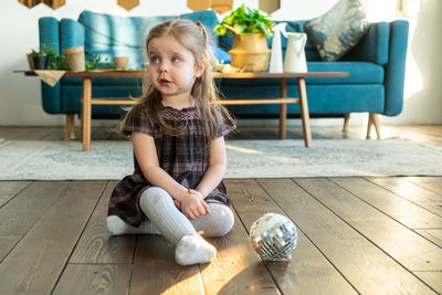 Cute girl looking away while sitting on floor