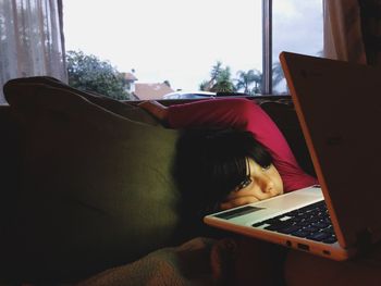 Rear view of woman using mobile phone at home