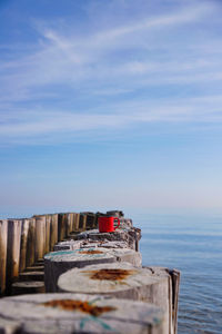 Wooden post on pier by sea against sky