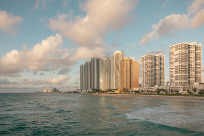 Sea by buildings against sky in city