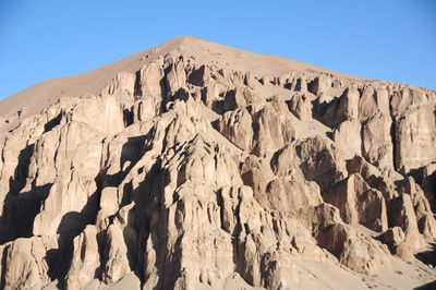 Low angle view of rocks against clear blue sky