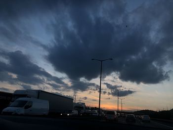 Cars on road against cloudy sky