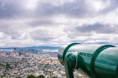 Close-up of telescope with city buildings in background