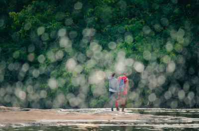 Man and woman standing by tree in forest
