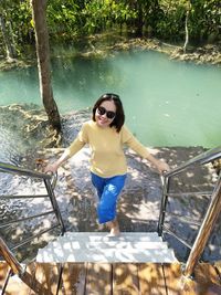 Full length of woman standing by railing against trees