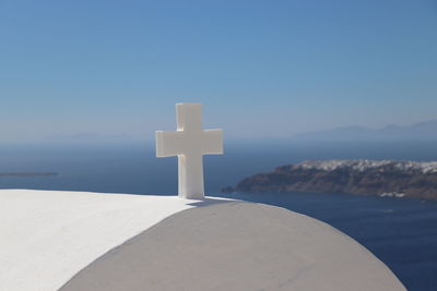 Cross by sea against blue sky