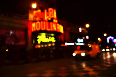 Defocused image of illuminated text on street at night