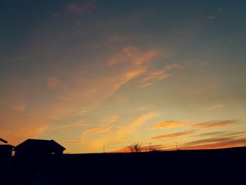 Silhouette houses against sky during sunset