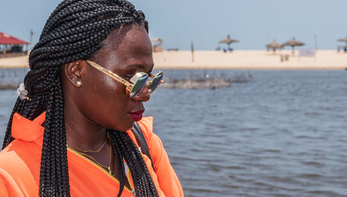 An african woman with round sunglasses from ghana is waiting for a boat on a sunny hot day in accra