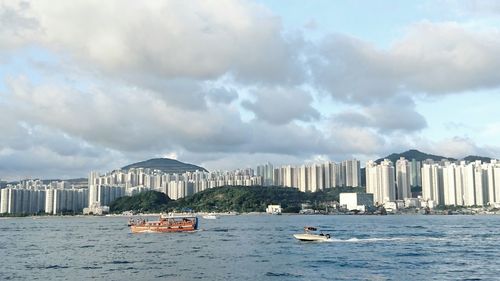 Boats in sea against cloudy sky