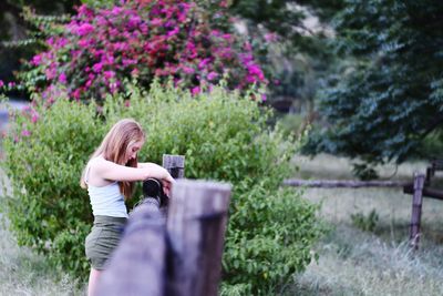 Side view of teenager standing by fence at park