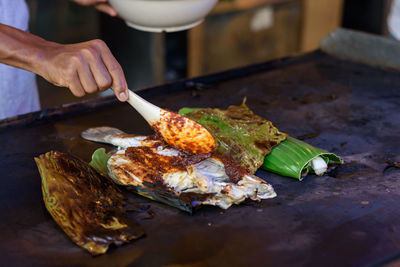 Cropped hands of person preparing fish on table