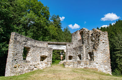 Rear view of young woman standing in gate of old fort ruin on a sunny summer day.