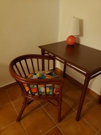 Empty chairs by table with lamp against wall at home