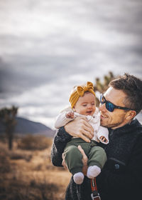 Rear view of father and son against cloudy sky