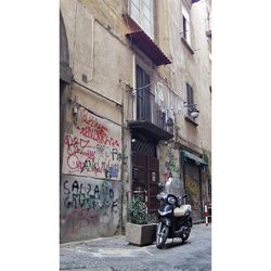 Man riding motor scooter on street against building