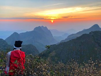 Rear view of man looking at mountains during sunset