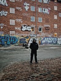 Full length of men standing against graffiti in city