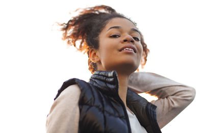 Portrait of young woman standing against white background