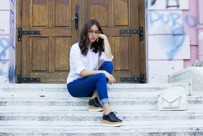 Full length portrait of young woman sitting outdoors