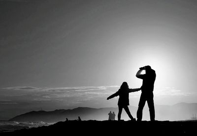 Silhouette men standing against sky