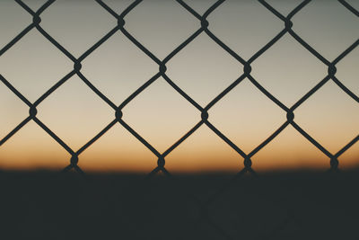 Close up of chainlink fence against evening backdrop.