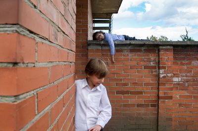 Full length of a girl standing against brick wall