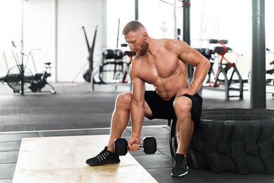 Full length of shirtless man exercising at gym