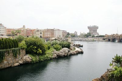 Bridge over river by buildings in city against clear sky