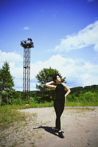 Beautiful young woman standing on field against sky