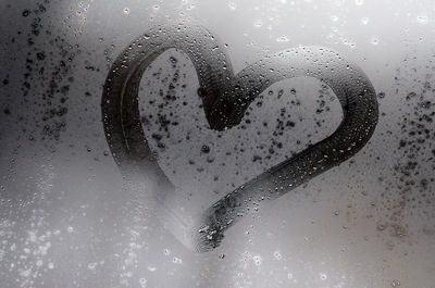 Close-up of heart shape on condensed glass window