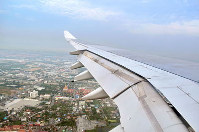 Airplane flying over cityscape against sky