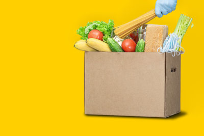 Various fruits in box against yellow background