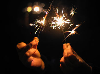 Hand holding firework display at night