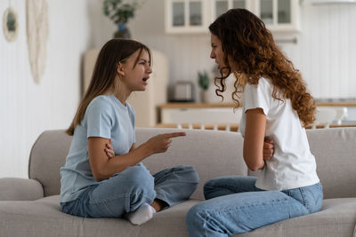 Young woman using digital tablet while sitting on sofa at home