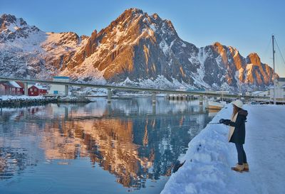 Side view of woman fishing in river during winter
