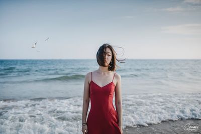 Woman standing at beach against sky