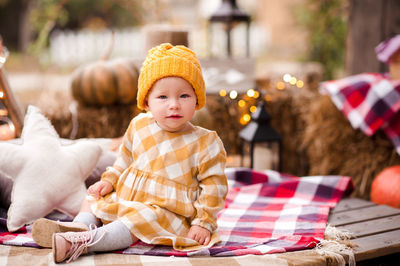 Portrait of cute girl sitting on blanket during autumn