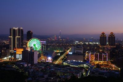 Illuminated buildings in city against sky at night