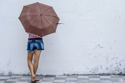 Saa woman from the back holding a brown umbrella on the street. salvador, bahia, bahia.