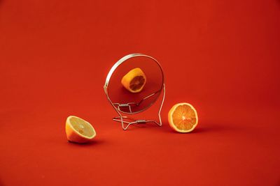 Mirror and orange fruits against red background