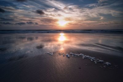 Reflection of sun at sandy beach during sunset