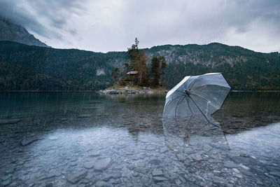 View of umbrella in lake against sky during rainy season