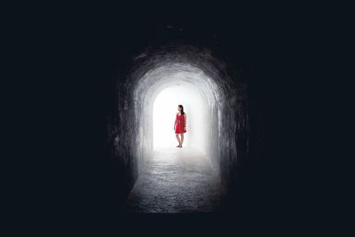 Full length of woman standing at illuminated tunnel entry