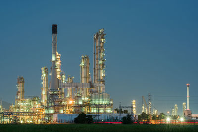 Illuminated factory against sky at night