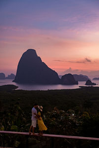 Woman standing on mountain against sky during sunset