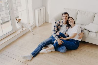 Portrait of couple sitting by sofa at home