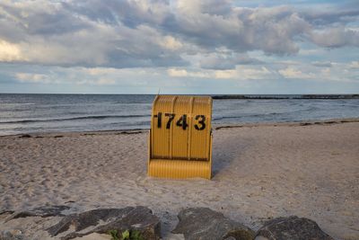 Information sign on beach against sky