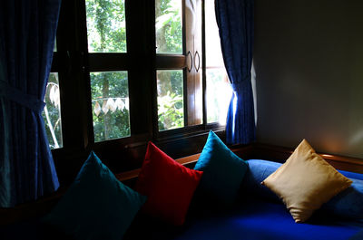 Cushions arranged on sofa against window at home