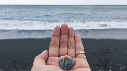 Close-up of hand holding stone at beach